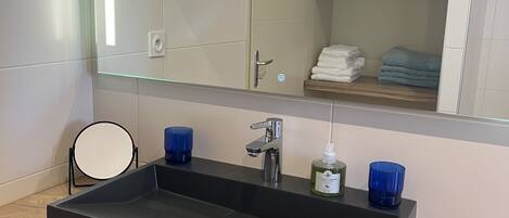 A modern bathroom with a rectangular sink, a mirror, and a wooden vanity.