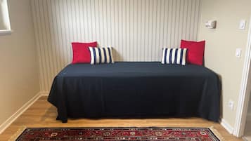 A bedroom with a bed, striped pillows, a patterned rug, and a striped wall.