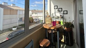 A balcony with a table, chairs, and potted plants.