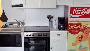 A modern kitchen with white cabinets, a built-in oven, a coffee maker, and a Coca-Cola advertisement.