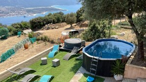 A backyard with a swimming pool, artificial grass, and lounge chairs.