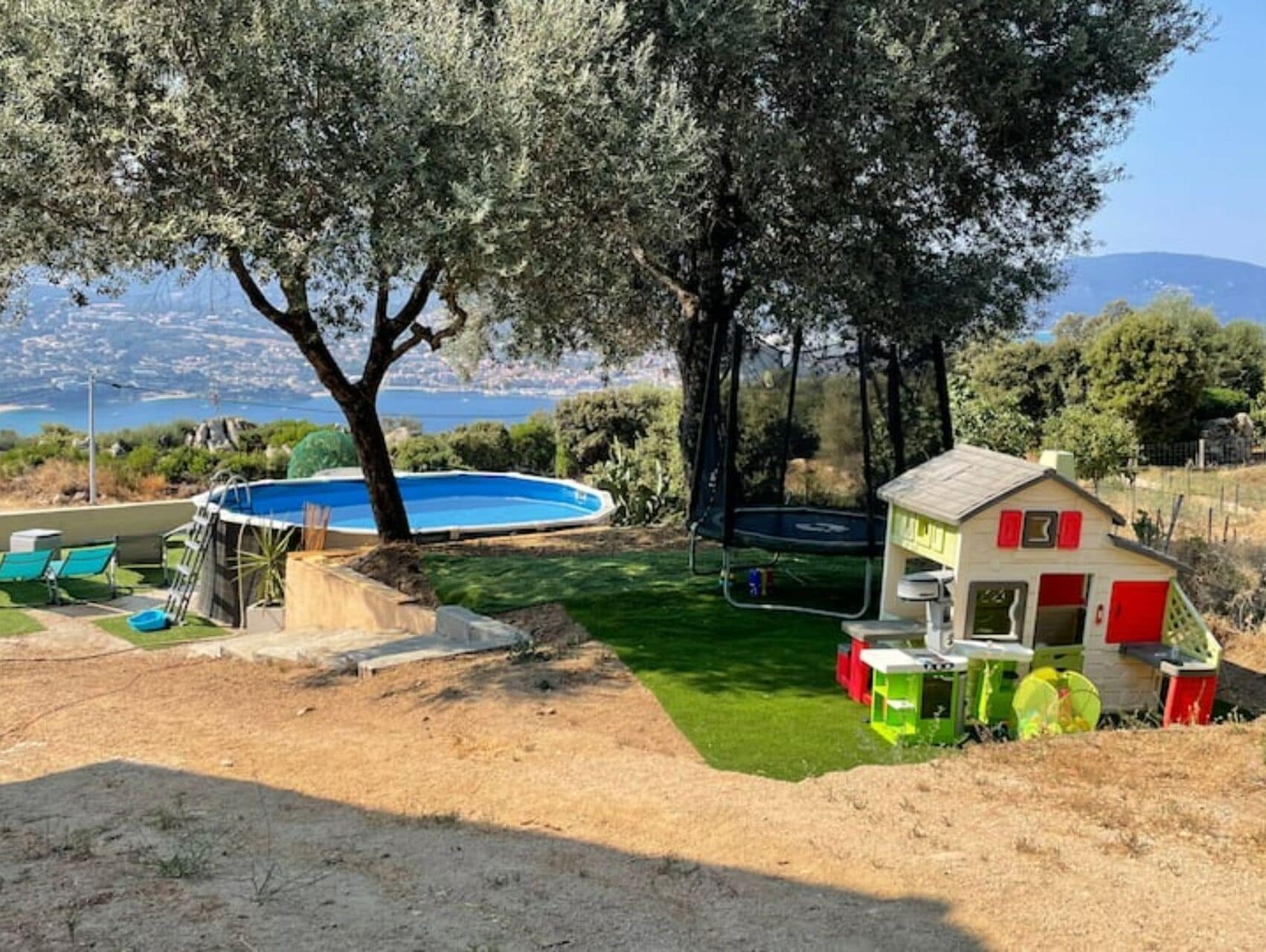 A backyard with a swimming pool, a trampoline, and a small shed.