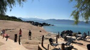 A beach with a patio area featuring outdoor seating and a view of the sea.