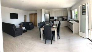 A modern living room with a black sofa and a dining area with a table and chairs.
