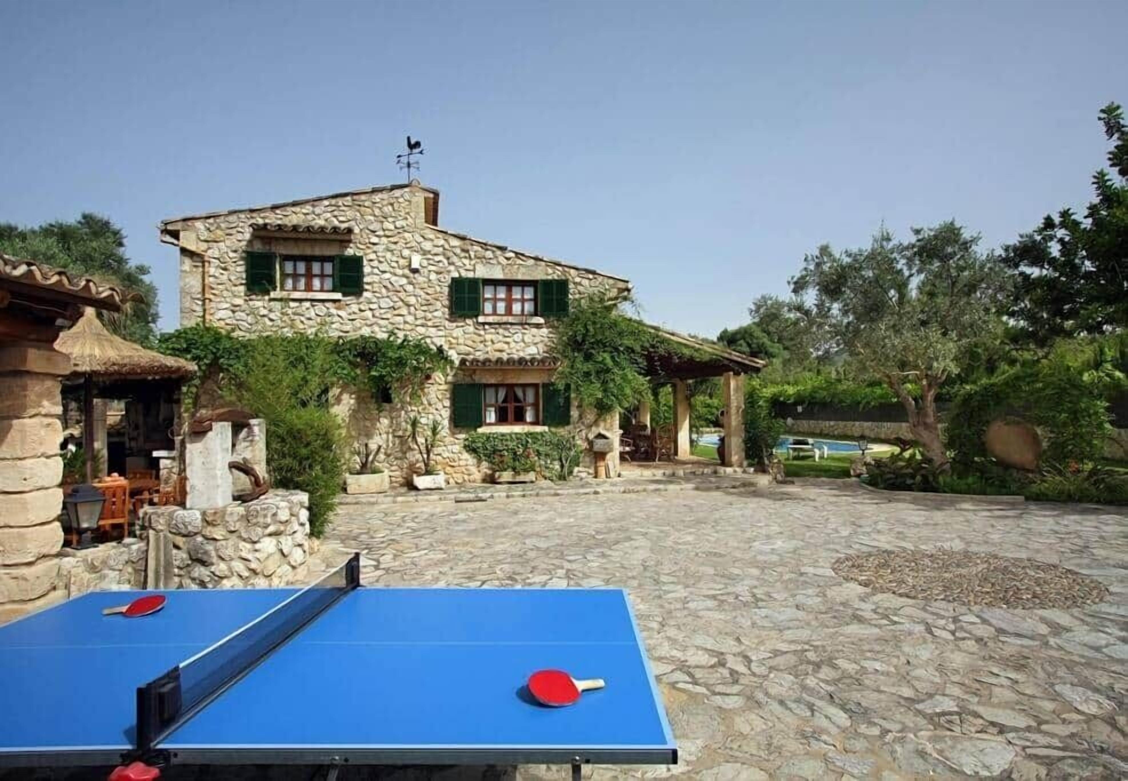Un bâtiment en pierre doté d’une cour, d’un espace extérieur aménagé pour s’asseoir et d’une table de ping-pong.