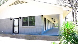 A building with a covered walkway, a gated entrance, and a series of windows.