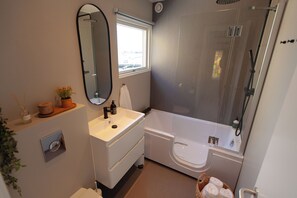A modern bathroom with a bathtub, a shower, a sink, and a mirror.
