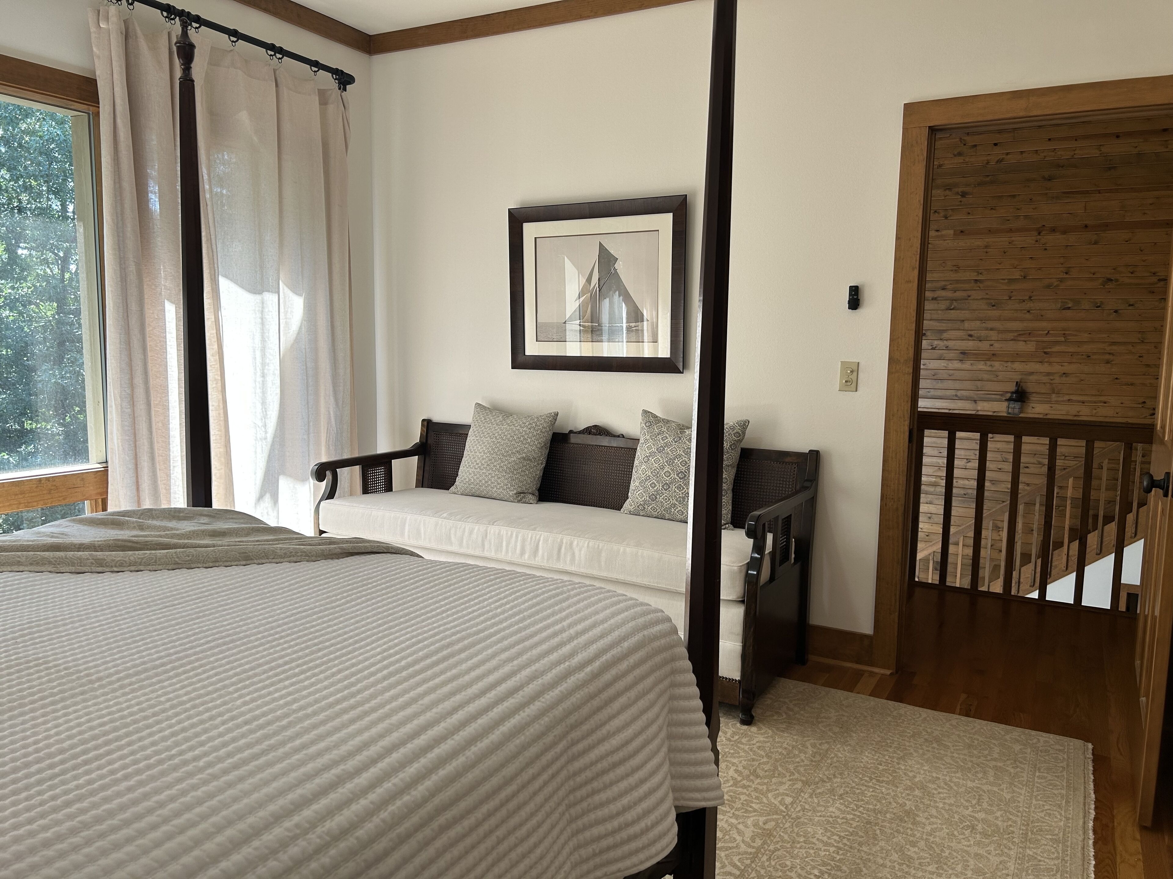 Une chambre avec un grand lit, un canapé, une porte en bois et une fenêtre avec des rideaux.