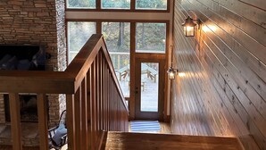 A wooden interior with a stone fireplace, large windows, and a wooden staircase. - Lakefront, 4Bdr+Loft, 3Ba, Boat Ramp, Golf, Ping Pong, Foosball, No Pets (Drasco)