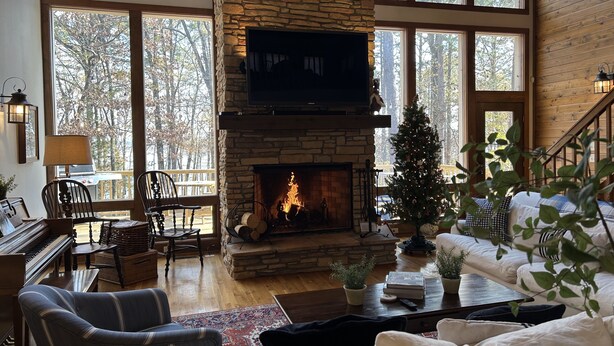 A cozy living room with a stone fireplace, a television, and a Christmas tree. - Lakefront, 4Bdr+Loft, 3Ba, Boat Ramp, Golf, Ping Pong, Foosball, No Pets (Drasco)
