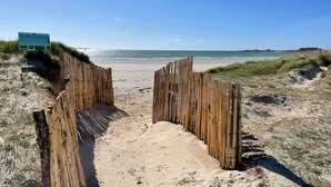 Une plage de sable bordée d’une clôture en bois qui mène à l’eau.