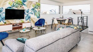 Un salon moderne avec un téléviseur à écran plat, un canapé, une table à manger et des chaises.