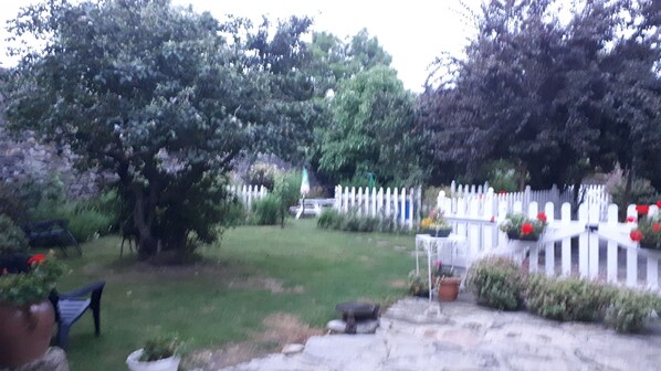 A garden with a white picket fence, a lawn, and a stone pathway.