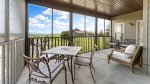 Eine überdachte Terrasse mit Tisch, Stühlen und einer Sitzecke, mit Blick auf die Landschaft.