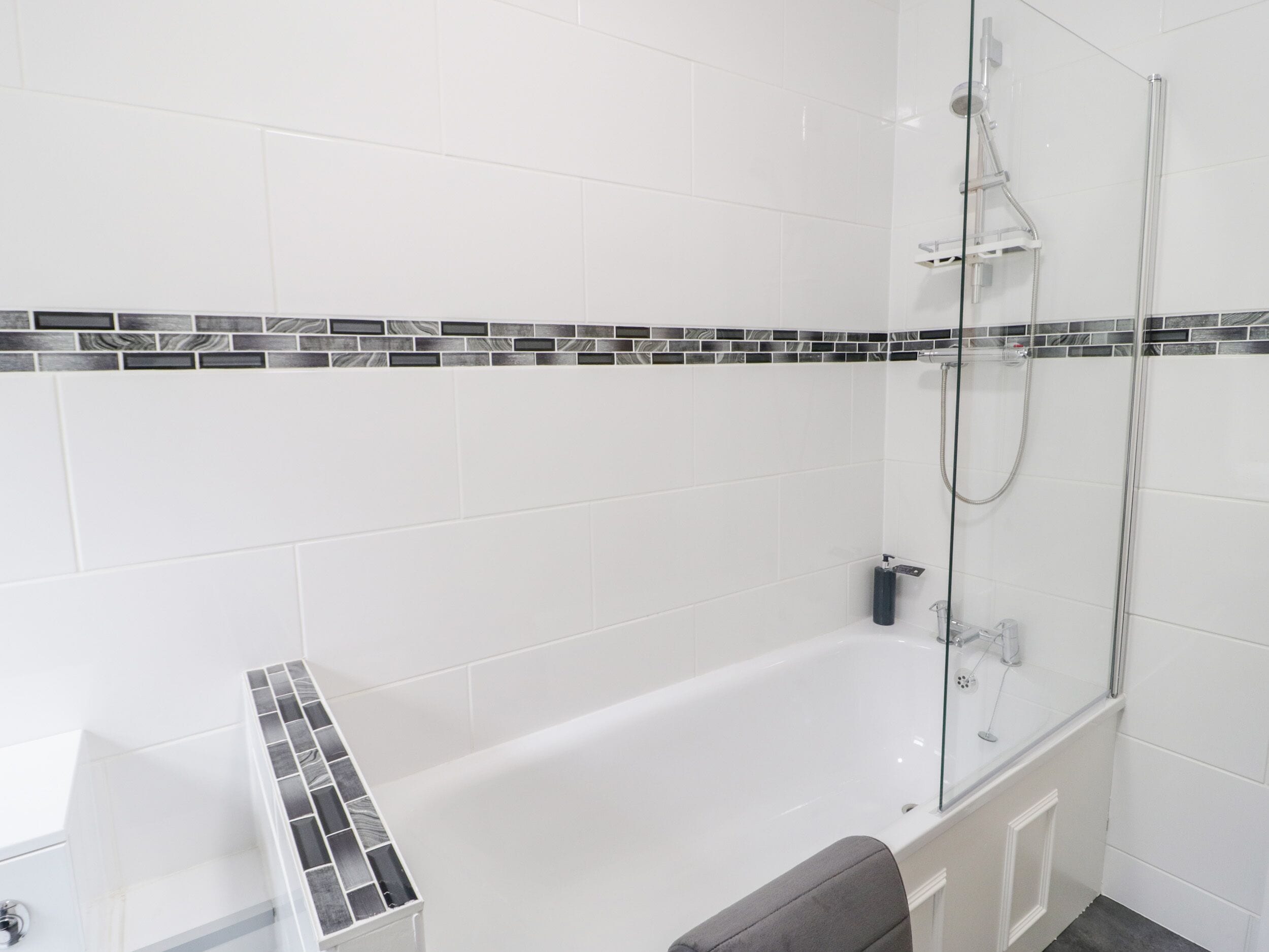 A modern bathroom with a bathtub, a glass shower enclosure, and a tiled backsplash.