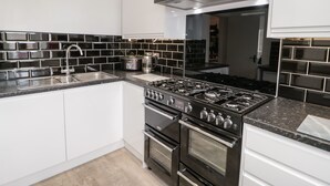 Une cuisine moderne dotée d’une cuisinière en acier inoxydable, d’un évier et d’un dosseret de carrelage noir.