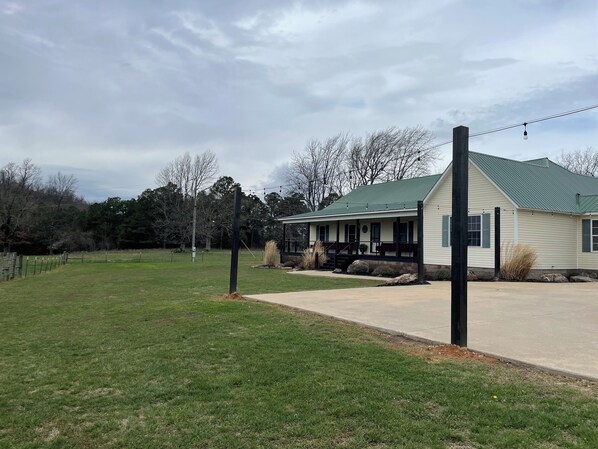 A single-story house with a green roof, a covered porch, and a well-maintained lawn.