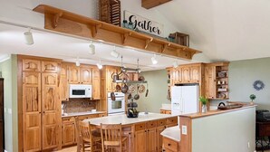 Une cuisine spacieuse avec des meubles en bois, un îlot central et un porte-casseroles suspendu.