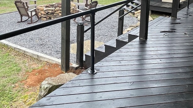 Un espace extérieur abrité, doté d’une terrasse en bois, d’un foyer en pierre et de fauteuils Adirondack.