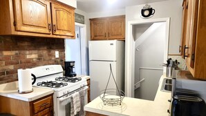 A kitchen with wooden cabinets, a gas stove, a refrigerator, a coffee maker, and a toaster. - Redford Tranquil Retreat (Redford Charter Township)