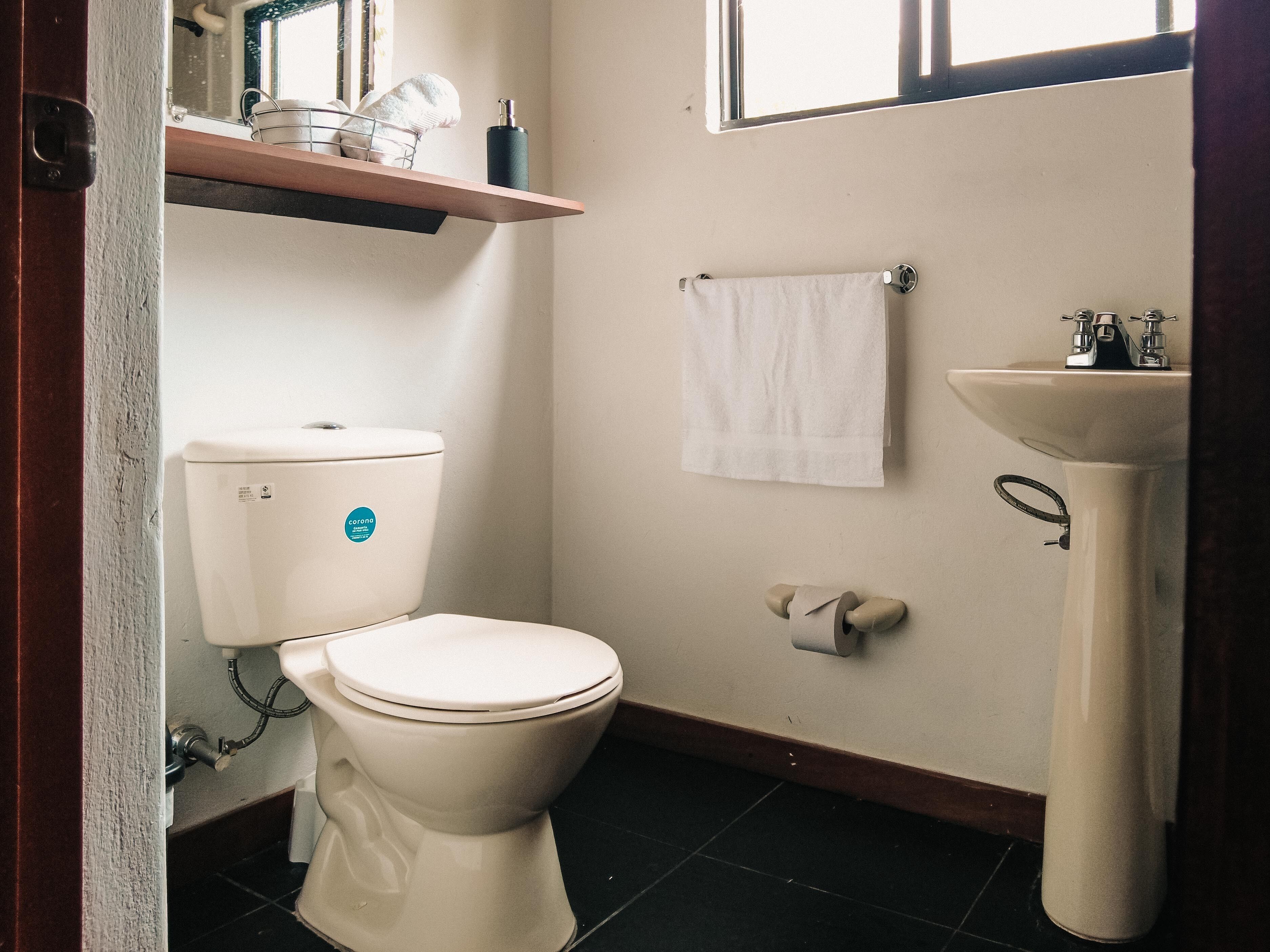 Ein kleines Badezimmer mit Toilette, Waschbecken und einem Handtuch an der Wand.