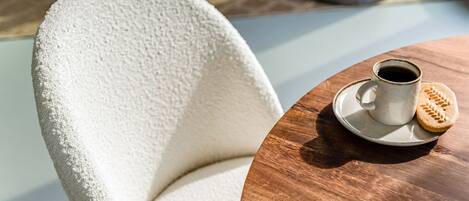 A round wooden table with a white ceramic mug and a biscuit.