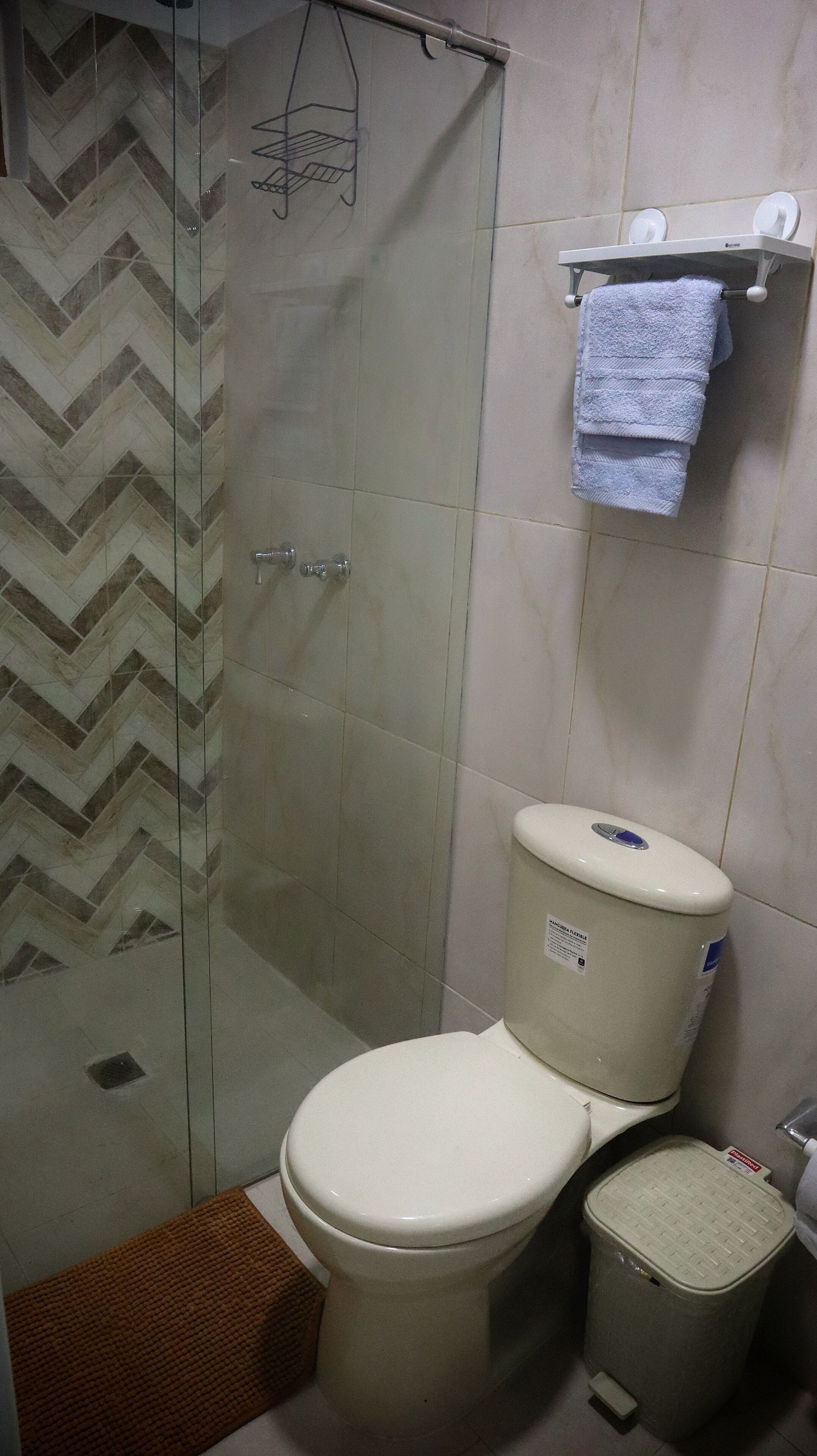 Un bagno con il water, una doccia e un cestino.
