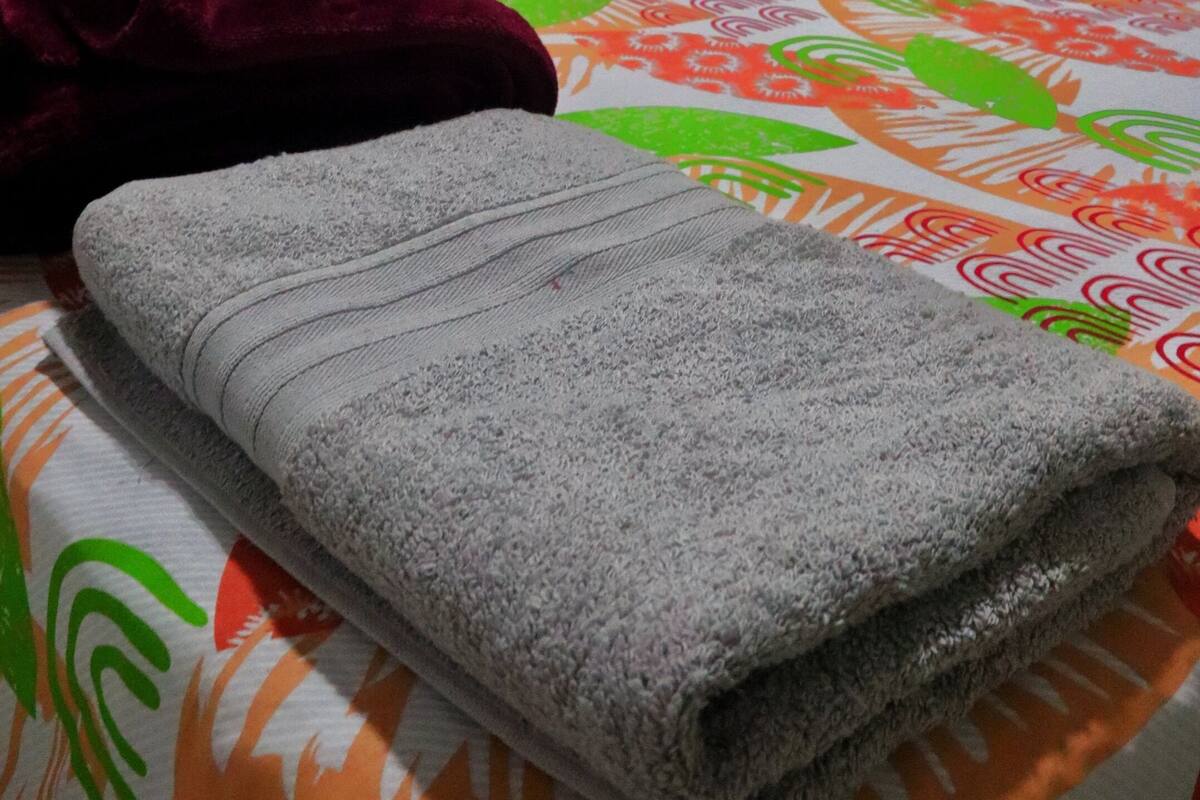 A bed with a floral bedspread, a green pillow, and a grey blanket.
