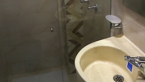 Un baño con cabina de ducha de vidrio, un lavabo con espejo y un perchero para toallas.