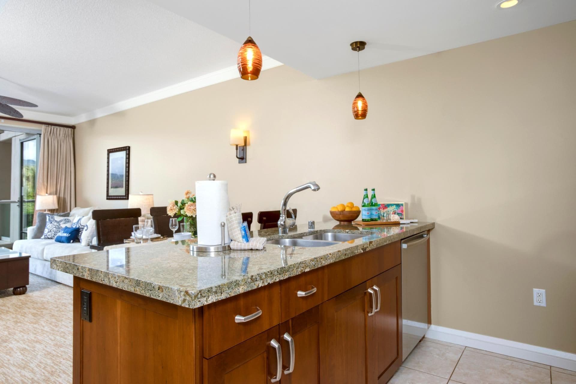 A kitchen with granite countertops, wooden cabinets, a sink, and pendant lighting.