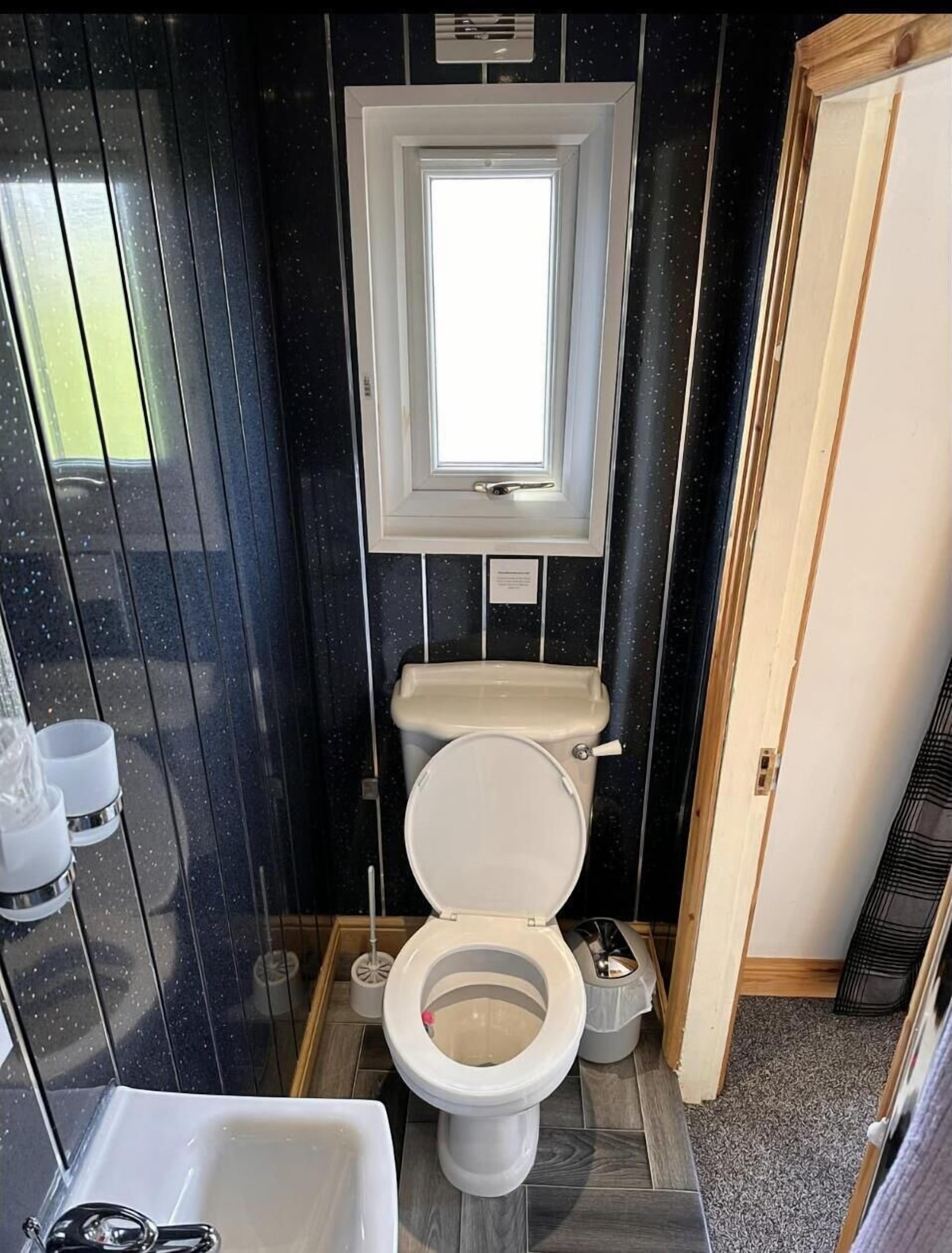 Ein kleines Badezimmer mit Toilette, einem Fenster und einem Waschbecken.