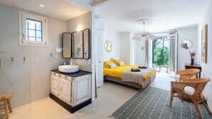 A modern bedroom with a large bed, a bathroom with a sink and mirrors, and a view of the outdoors. - Large Mas in the Roussillon pine forest, heated swimming pool (Gargas)