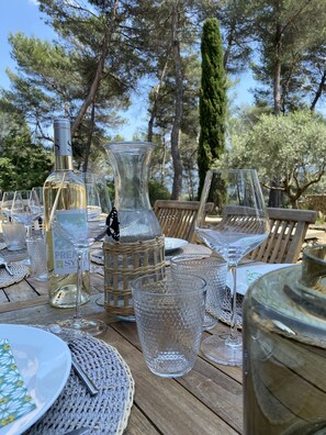 A wooden table set outdoors with wine glasses, a bottle, and a decorative pitcher. - Large Mas in the Roussillon pine forest, heated swimming pool (Gargas)