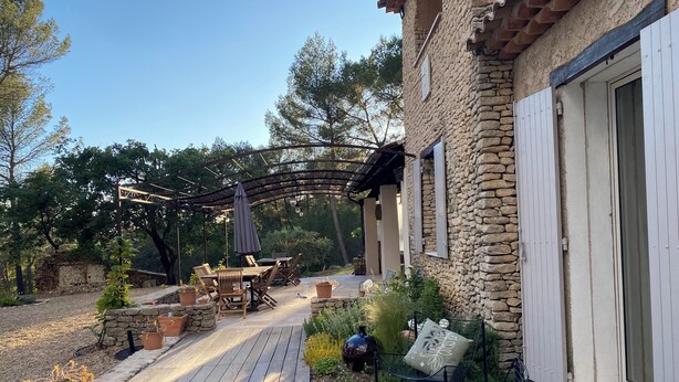A stone building with a wooden deck, outdoor seating, and a pergola. - Large Mas in the Roussillon pine forest, heated swimming pool (Gargas)