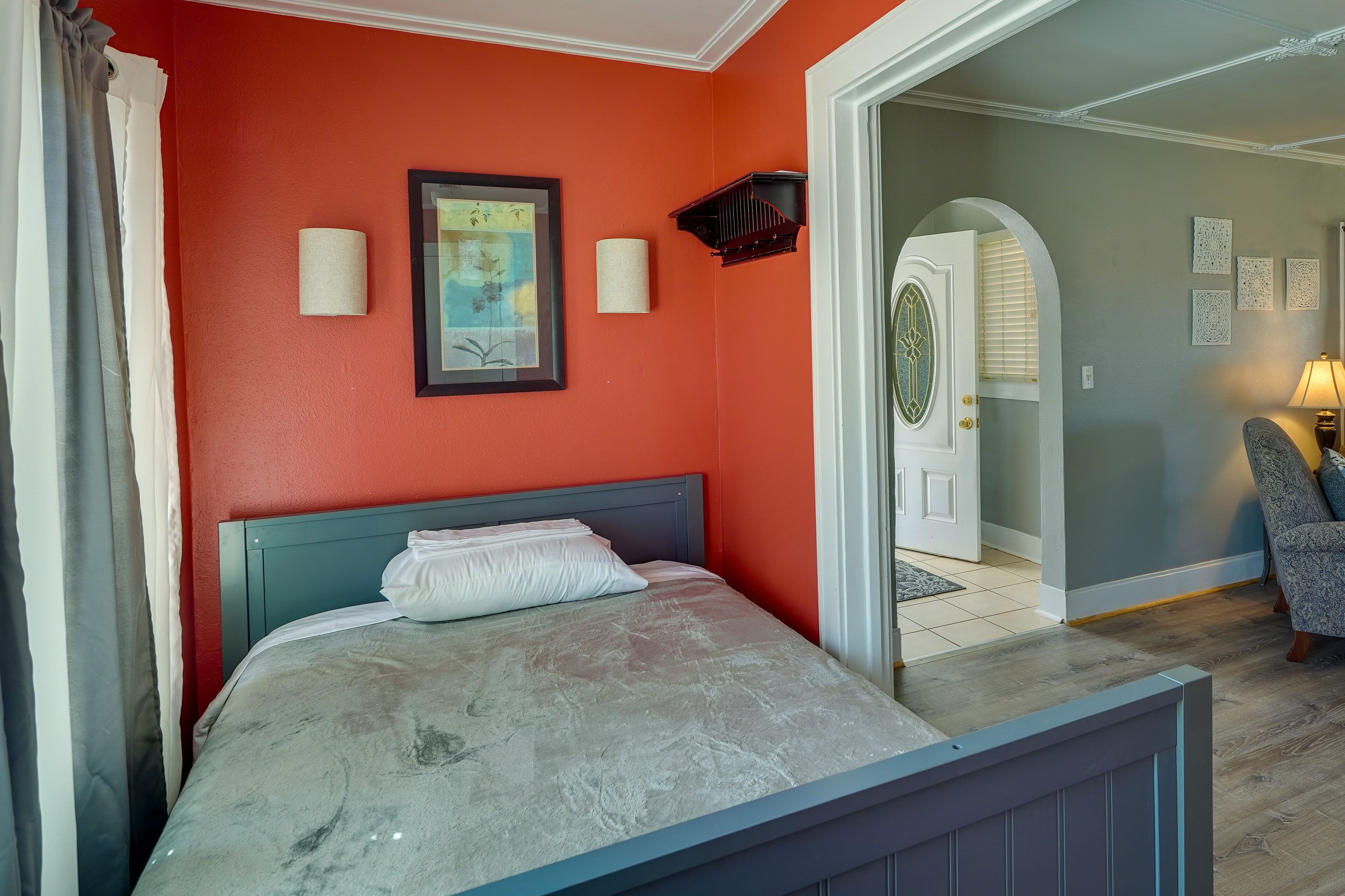 Een slaapkamer met een bed, een ingelijste foto en een deur naar een andere kamer.