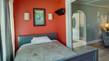 Een slaapkamer met een bed, een ingelijste foto en een deur naar een andere kamer.