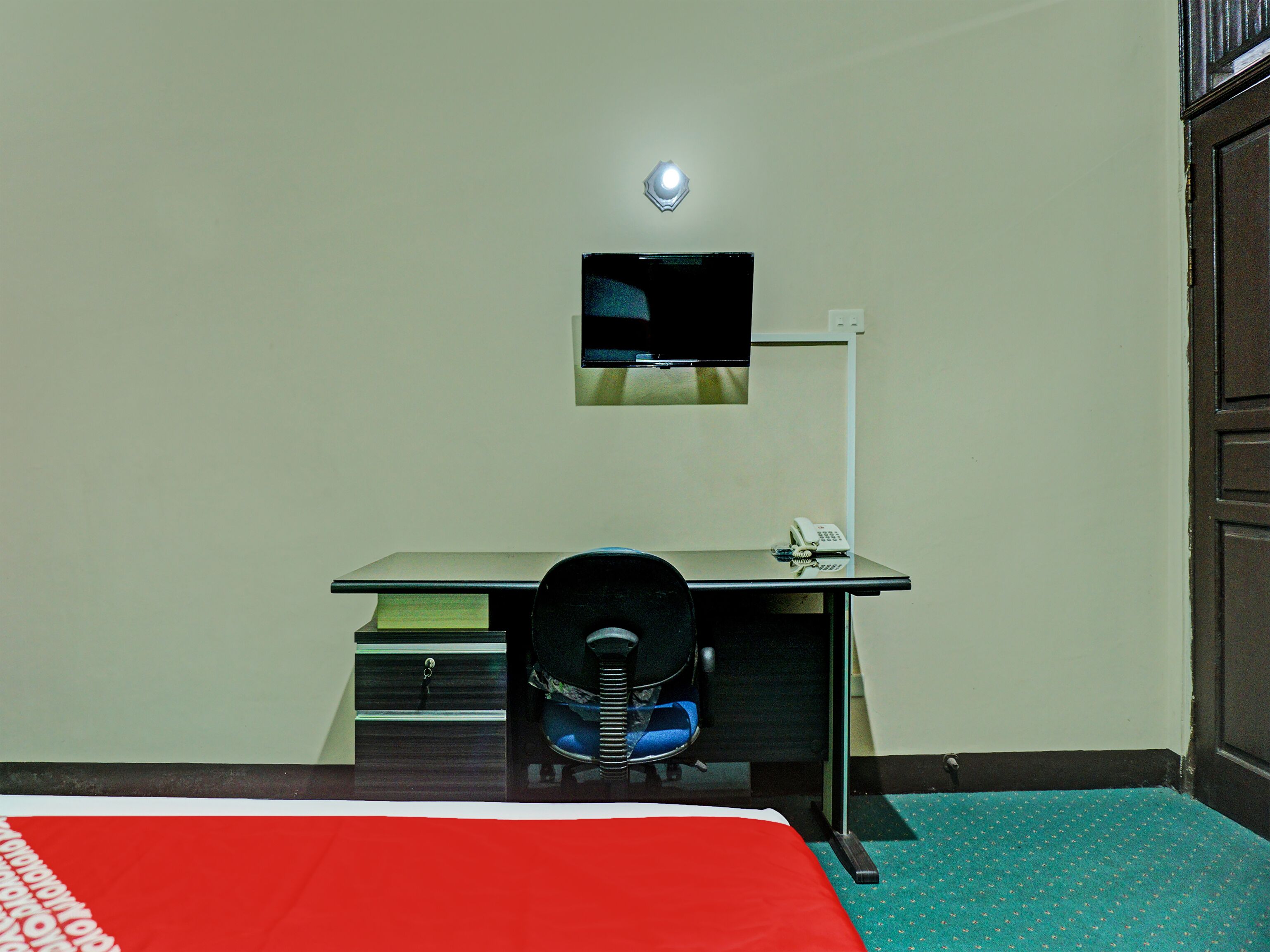 Une chambre d’hôtel équipée d’un lit, d’un bureau, d’une chaise, d’un téléviseur fixé au mur et d’un téléphone.