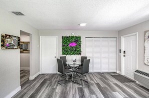 A room with a dining table and chairs, a white door, a closet, and a wall-mounted plant. - 🌴 Beach Getaway | Hot Tub | Pets OK! | Fire Pit 🌴 (West Palm Beach)