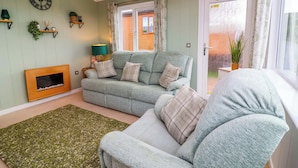 Ein gemütliches Wohnzimmer mit Sofa, Sessel und Kamin.