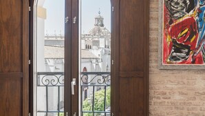 Ein Zimmer mit einer großen Holztür, die auf einen Balkon mit Blick auf ein historisches Gebäude führt.