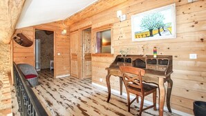 Un interior de madera con una mesa y sillas para comer, un cuadro en la pared y un ventanal.