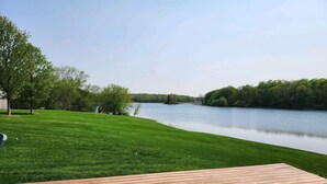 Une terrasse en bois offrant une vue sur un lac et des arbres.