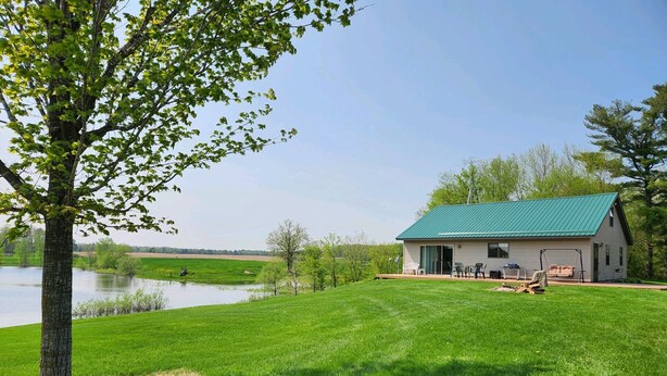 Une maison avec un toit végétalisé, une pelouse et un étang en arrière-plan.