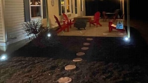 A cabin with a covered patio area, outdoor seating, and a fire pit.