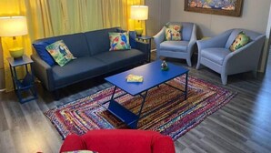 A living room with a sofa, two armchairs, a coffee table, and a colorful rug.