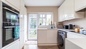 Eine kompakte Küche mit Einbauofen, Waschmaschine und Spüle.