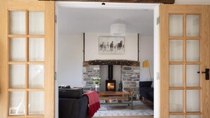 Una sala de estar acogedora con chimenea de piedra, muebles de madera y una obra de arte enmarcada en la pared.