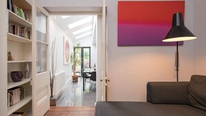 Una sala de estar moderna con un sofá gris, una lámpara de pie negra y una estantería llena de libros.