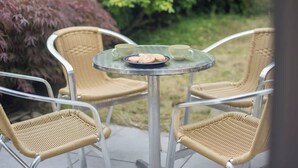 Una mesa redonda de cristal con dos sillas, un plato con galletas y vistas a un jardín.