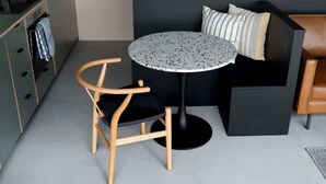 A compact room with a round table, a chair, a sofa, and a kitchenette area. - Subterranean Studio with Panoramic Views & Sauna (Pembrokeshire)